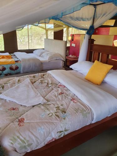 Masai Mara Explore Camp في Narok: غرفة نوم بسريرين ومظلة