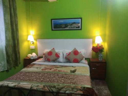 1 dormitorio con 1 cama con paredes verdes y 2 lámparas en Beverly Hills Home stay, en Darjeeling