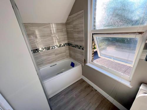 a small bathroom with a tub and a window at Exeter Road Rooms in South Norwood