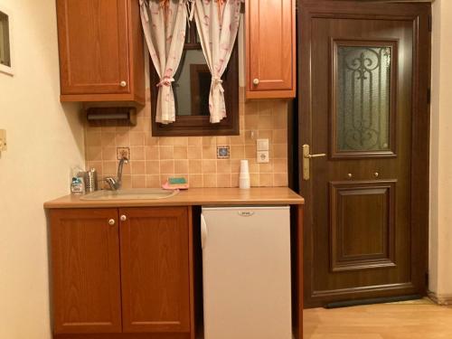 een keuken met een wastafel, een koelkast en een deur bij Pool House Stamato in Kineta