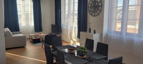 - un salon avec une table, des chaises et une horloge dans l'établissement T2 neuf hypercentre 5 couchages, à Saint-Quentin