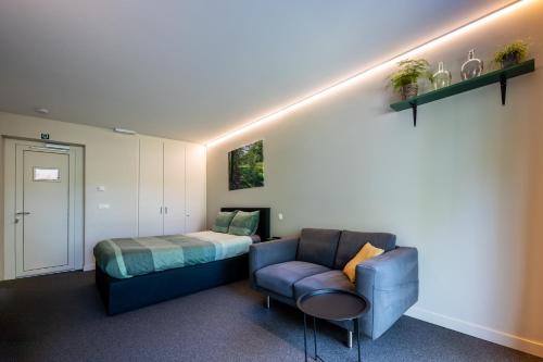 Zimmer mit einem Sofa, einem Bett und einem Stuhl in der Unterkunft Bleekhoeve in Olen