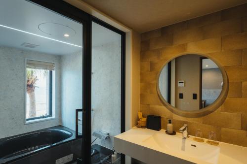 ein Badezimmer mit einer Badewanne, einem Waschbecken und einem Spiegel in der Unterkunft L'isola THE BIRD in Kami Amakusa