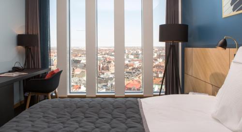 a hotel room with a bed and a desk and windows at Clarion Hotel Malmö Live in Malmö
