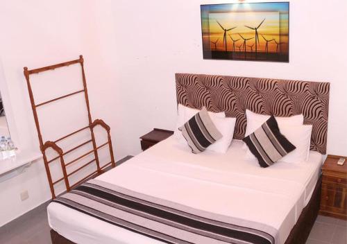 Cozy Inn Negombo في نيجومبو: غرفة نوم بسرير ذو شراشف بيضاء ومخدات سوداء وبيضاء