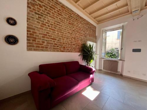 a red couch in a living room with a brick wall at Dimora Boezio7, cozy and charming place in center with private parking in Pavia