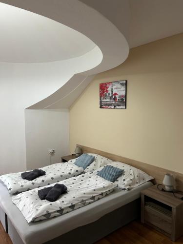 a bedroom with a bed with white sheets and blue pillows at Kondé Apartments A in Dunajská Streda