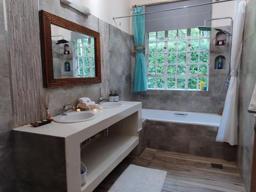 een badkamer met 2 wastafels, een bad en een raam bij Kisuri Resort 