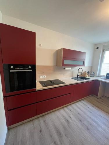a large kitchen with red cabinets and a sink at Großzügige Wohnung in Lüdenscheid