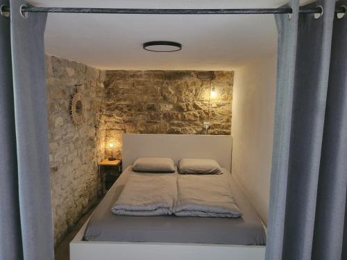 Cama en habitación con pared de piedra en Maison des biches, en Saint-Jean-et-Saint-Paul