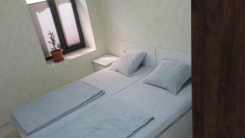 białe łóżko z 2 poduszkami i oknem w obiekcie Begzod's house w Samarkandzie