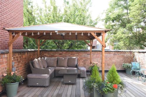 a wooden gazebo with a couch and table on a deck at The Hop Merchant's House in Worcester