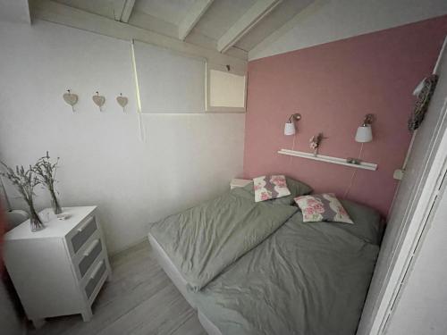 a small bedroom with a bed and a pink wall at Casita di Ellinor in Tignale