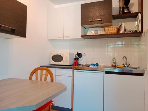 une cuisine avec un évier et un micro-ondes dans l'établissement Les Rosiers, à Challans