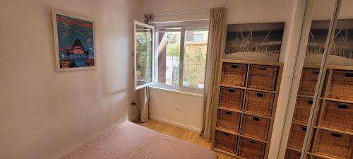 Cette chambre comprend un lit, une fenêtre et des paniers. dans l'établissement Pesquiers T2 grande terrasse, à Hyères