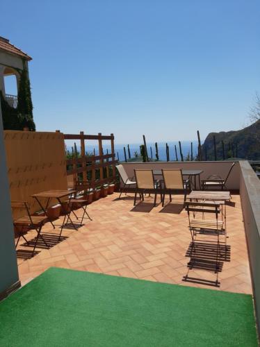 a patio with chairs and tables and a green rug at Villa Mariel Suites & Apartment in Massa Lubrense
