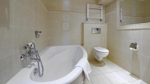 a white bathroom with a tub and a toilet at Hotel Diament Arsenal Palace Katowice - Chorzów in Chorzów