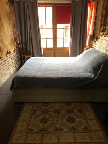 a bedroom with a bed and a window and a rug at La Maison aux Volets Rouges in La Ferté-Beauharnais