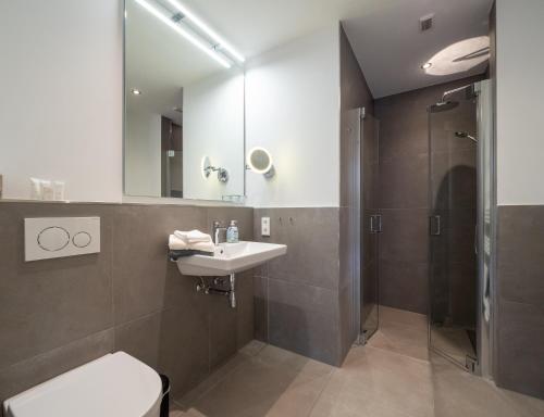 a bathroom with a toilet and a sink and a shower at Inselsünn Hotel und Apartments in Spiekeroog