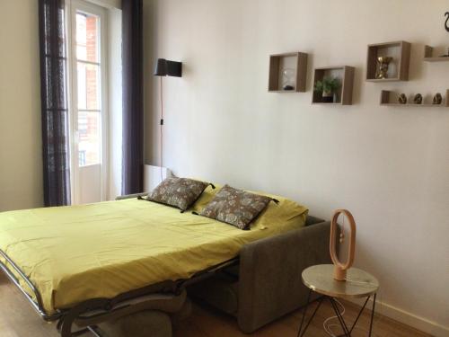 - une chambre avec un lit avec des draps jaunes et une chaise dans l'établissement La halle aux grains, à Toulouse