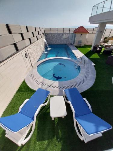duas cadeiras azuis e brancas e uma piscina em Sea view chalet em Taba