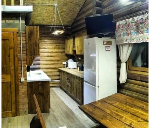 a kitchen with a white refrigerator and wooden walls at Шаленарозі in Migovo