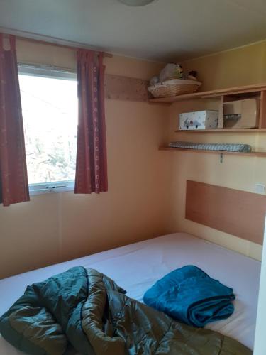 a small bedroom with a bed with a window at Mobilhome Vue mer et nature in Plougastel-Daoulas