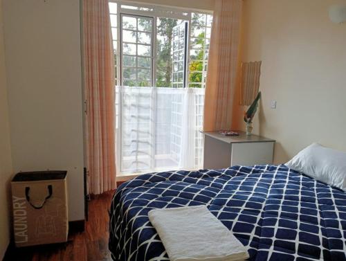 een slaapkamer met een blauw en wit bed en een raam bij BomaBnB Holiday Homes in Nairobi