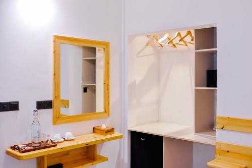 a bathroom with a mirror and a wooden shelf at Dhoani Maldives Guesthouse in Kendhoo