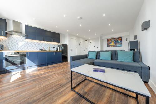 a living room with a blue couch and a kitchen at 4 West London Brand New Loft in London