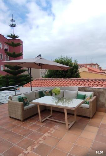 a patio with a couch and an umbrella at Vivienda Villalvaro in Santander