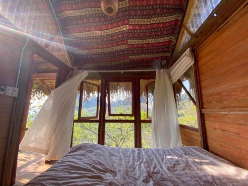 Bett in einem Zimmer mit einem großen Fenster in der Unterkunft Hali Home Moc Chau in Mộc Châu