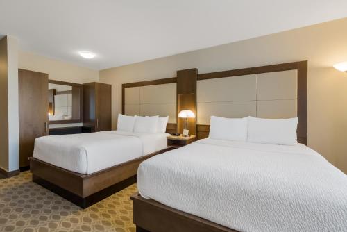 two beds in a hotel room with white sheets at Hotel 11, MOD A Sonesta Collection in Calgary
