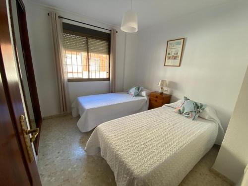1 dormitorio con 2 camas y ventana en Apartamento Familiar En Barrio Reina Victoria, en Huelva