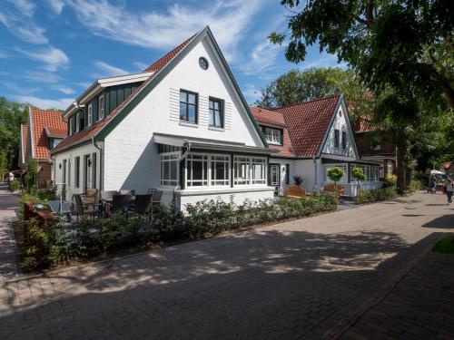 a white house with a red roof on a street at Inselsünn Hotel und Apartments in Spiekeroog