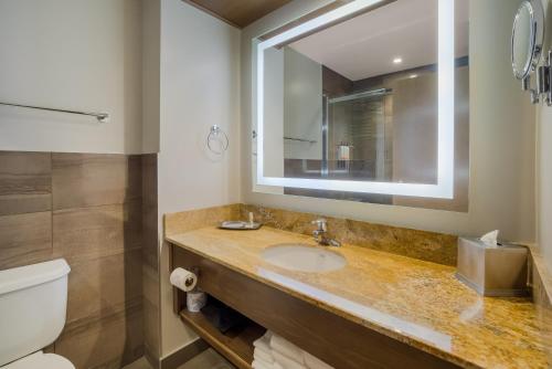 a bathroom with a sink and a toilet and a mirror at Hotel 11, MOD A Sonesta Collection in Calgary