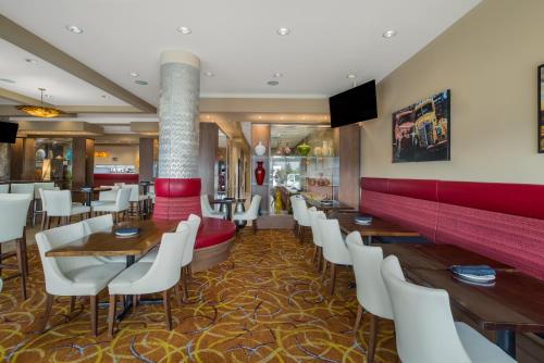 a restaurant with wooden tables and white chairs at Hotel 11, MOD A Sonesta Collection in Calgary