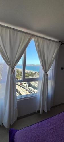 a bedroom with a window with a view of the ocean at ARRIENDO DEPARTAMENTO AVDA .DEL MAR LA SERENA, CHILE in Coquimbo