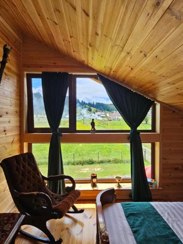 a bedroom with a bed and a chair in front of a window at La Căsuță in Vatra Dornei