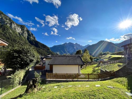 una casa en un valle con montañas en el fondo en Baitèl - Tra il cielo e le Alpi, en Gromo