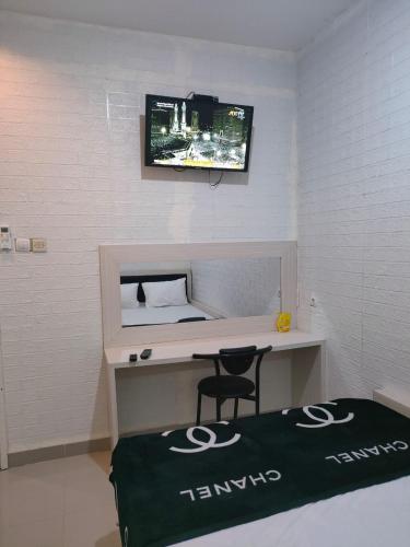 a room with a desk with a tv on the wall at Cahaya Losmen Sragen Syariah in Sragen