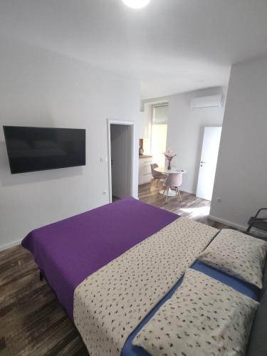 a bedroom with a large bed with a purple blanket at Studio apartman Mara in Imotski