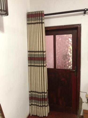 a door with a curtain next to a window at Gamage Stay Madiha in Matara