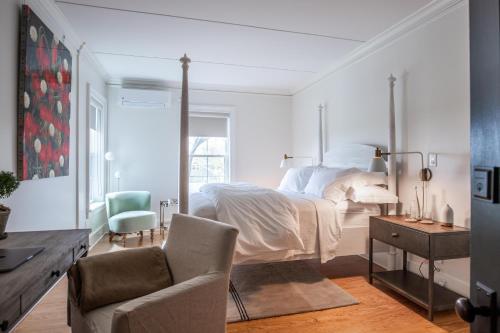 a white bedroom with a bed and a chair at Vine & Sand--Southold NY's Newest B&B in Southold