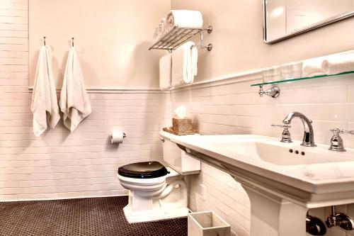 La salle de bains blanche est pourvue de toilettes et d'un lavabo. dans l'établissement Vine & Sand--Southold NY's Newest B&B, à Southold
