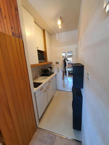 une cuisine avec une personne traversant un couloir dans l'établissement Les Gentianes n°8 - Studio en centre de station. Vue sur les pistes., à Besse-et-Saint-Anastaise