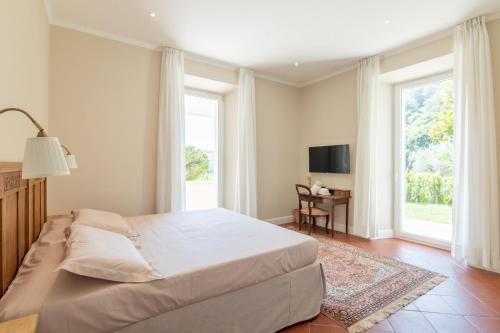 a bedroom with a bed and a table and windows at B&B Villa Eden jacuzzi pool in Domaso