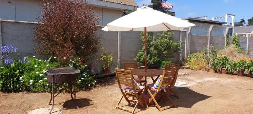 a table and chairs with an umbrella and a grill at Casa para 4 personas, en El Quisco Norte in El Quisco
