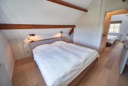 a bedroom with a large white bed in a room at Villa Magnolia in Oostkapelle