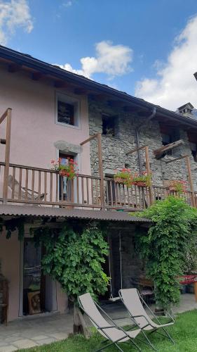 2 chaises assises à l'extérieur d'une maison avec balcon dans l'établissement Il canto del bosco, à Valpelline